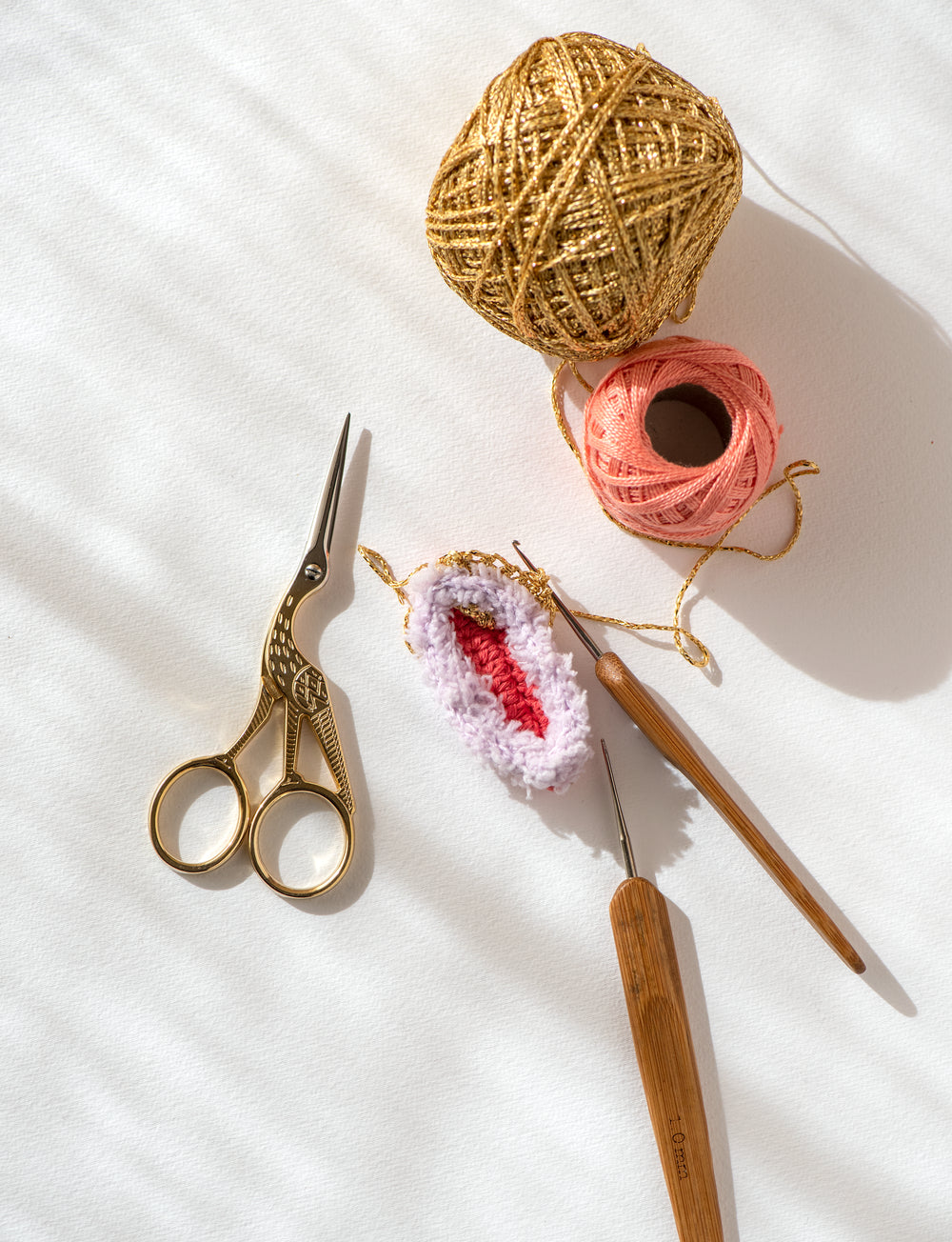 ciseaux, crochets et pelotes de fils doré et rose pour l'atelier de crochet à Montréal