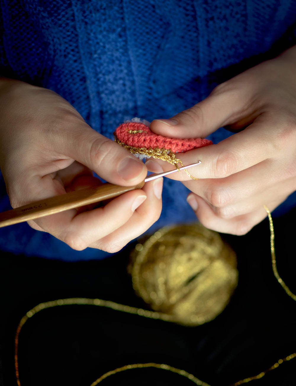 mains de l'artiste Agathe Dessaux en train de crocheter avec du fil doré pour l'atelier de crochet à Montréal. 